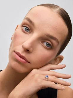 Anillo de oro blanco de 18K con zafiro azul en talla oval de 0,91 cts y orla de diamantes en talla brillante con un total de 0,37 cts
