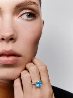 Anillo de oro blanco de 18K con topacio azul sky en talla oval de 5,8 cts y 12 diamantes en talla brillante con un total de 0,3 cts