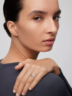 Anillo de oro blanco de 18K con zafiro azul en talla brillante de 0,35 cts y orla y brazo de 24 diamantes en talla brillante con un total de 0,32 cts