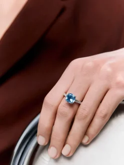 Anillo de oro blanco de 18K con topacio azul sky en talla cushion de 3,72 cts y 12 diamantes en talla brillante con un total de 0,3 cts