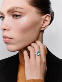 Anillo de oro blanco de 18K con topacio azul sky en talla oval de 5,8 cts y 12 diamantes en talla brillante con un total de 0,3 cts