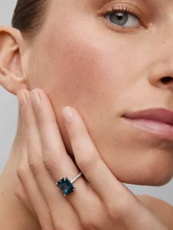 Anillo de oro blanco de 18K con topacio azul london en talla esmeralda de 4,25 cts y 14 diamantes en talla brillante con un total de 0,32 cts