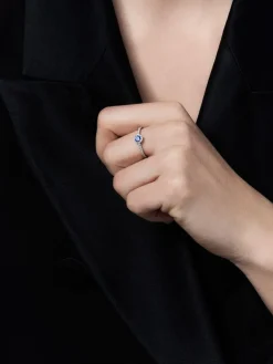 Anillo de oro blanco de 18K con zafiro azul en talla brillante de 0,26 cts y orla y brazo de 26 diamantes en talla brillante con un total de 0,26 cts