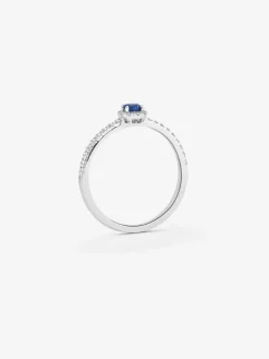 Anillo de oro blanco de 18K con zafiro azul en talla brillante de 0,26 cts y orla y brazo de 26 diamantes en talla brillante con un total de 0,26 cts