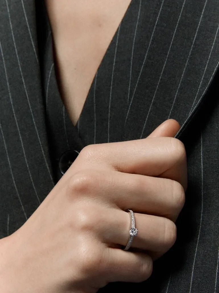 Anillo solitario de oro blanco de 18K con un diamante central en talla brillante de 0,23 cts y brazo de 29 diamantes en talla brillante con un total de 0,12 cts