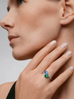 Anillo tú y yo de oro blanco de 18K con un zafiro azul intenso en talla pera de 1,49 cts, una esmeralda verde en talla pera de 1,04 cts y 14 diamantes en talla brillante con un total de 0,64 cts
