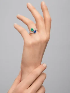 Anillo tú y yo de oro blanco de 18K con zafiro azul intenso en talla pera de 1,93 cts, esmeralda verde en talla pera de 0,89 cts y 14 diamantes en talla brillante con un total de 0,89 cts