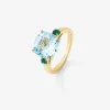 Anillo tresillo de oro amarillo de 18K con topacio azul sky en talla cushion de 4,88 cts y 2 esmeraldas verdes en talla brillante