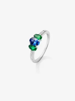 Anillo tresillo de oro blanco de 18K con zafiro azul en talla oval de 0,72 cts, 2 esmeraldas verdes en talla oval con un total de 0,36 cts y 16 diamantes en talla brillante con un total de 0,14 cts