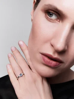Anillo tresillo de oro blanco de 18K con zafiro azul en talla oval de 0,48 cts y 2 diamantes en talla brillante con un total de 0,24 cts