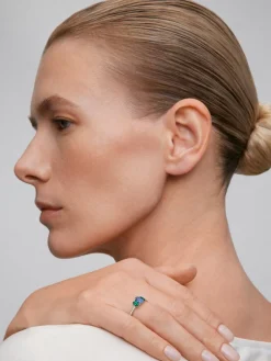 Anillo tresillo de oro blanco de 18K con zafiro azul en talla oval de 0,72 cts, 2 esmeraldas verdes en talla oval con un total de 0,36 cts y 16 diamantes en talla brillante con un total de 0,14 cts