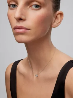 Colgante de oro blanco de 18K con diamante central en talla brillante de 0,2 cts y orla de 2 diamantes en talla baguette con un total de 0,05 cts y 10 diamantes en talla brillante con un total de 0,035 cts
