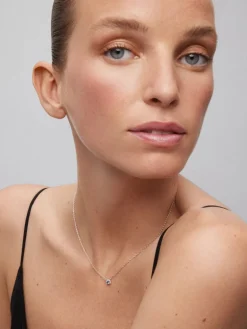 Colgante de oro blanco de 18K con zafiro azul en talla brillante de 0,23 cts y orla de 10 diamantes en talla brillante con un total de 0,07 cts