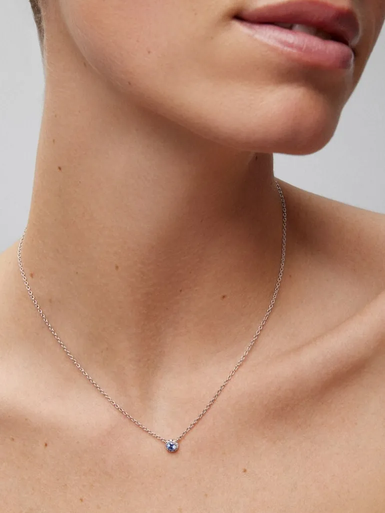 Colgante de oro blanco de 18K con zafiro azul en talla brillante de 0,23 cts y orla de 10 diamantes en talla brillante con un total de 0,07 cts