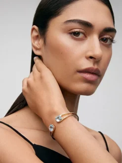 Pulsera r&iacute;gida de oro amarillo de 18K con 2 topacios azul sky en talla cushion con un total de 0,12 cts