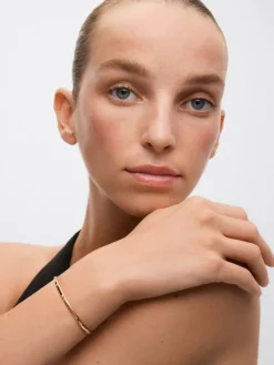 Pulsera r&iacute;gida de oro amarillo de 18K con 3 diamantes en talla brillante con un total de 0,07 cts