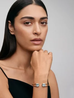 Pulsera r&iacute;gida de oro amarillo de 18K con 2 topacios azul sky en talla cushion con un total de 0,12 cts