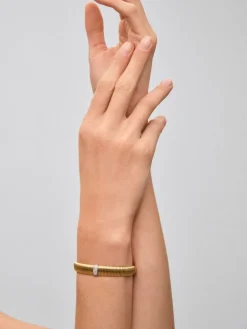 Pulsera r&iacute;gida gallonada de oro blanco y amarillo de 18K con pavé de diamantes en talla brillante con un total de 0,16 cts